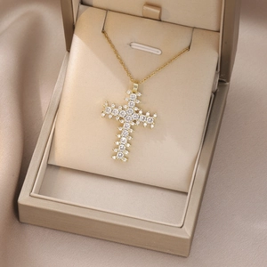 Detail of cross pendant necklace with sparkling white stones in a gold gift box