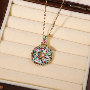 Detail einer Goldkette mit einem bunten, mit Zirkon besetzten Donut-Ring-Anhänger