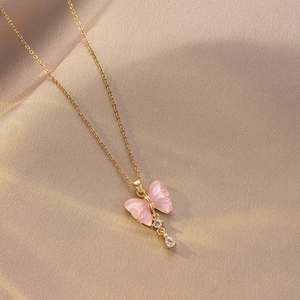 Detalle del collar de mariposa dorada con alas rosas y circón blanco de gota