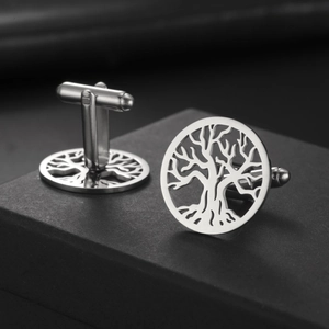 Close-up of circular cufflinks featuring a detailed tree of life cutout in polished silver metal