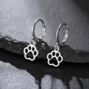 Macro shot of 304 stainless steel paw print earrings on a dark stone background