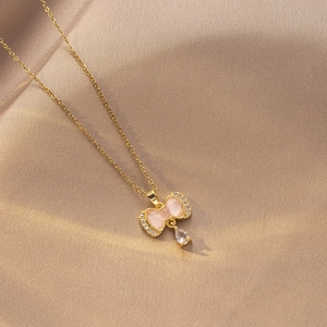 Detalle del collar de mariposa con piedra ojo de gato rosa y circón en seda champán