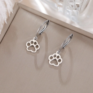 Close-up of silver stainless steel hollow paw print earrings on a jewelry display mat