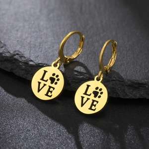 Detailed macro shot of golden stainless steel hoop earrings with cutout paw print and love text