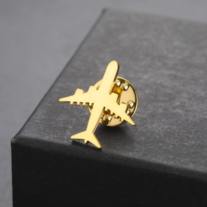 Macro d'une broche avion dorée avec fermoir papillon sur boîte cadeau élégante
