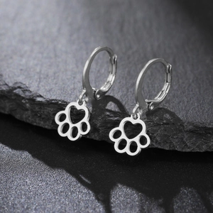 Detailed macro view of silver stainless steel paw print earrings with heart cutout detail