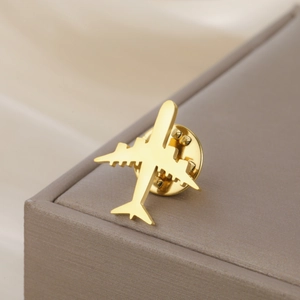 Détail d'une broche avion en acier inoxydable doré sur un écrin à bijoux marron