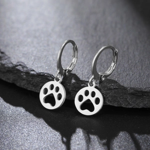 Macro view of silver stainless steel hoop earrings with hollow paw print pendant charms