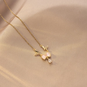 Detalle del collar de mariposa dorado con piedra ojo de gato rosa y gota de circón