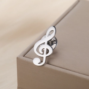 Détail macro d'une broche note de musique argentée avec attache papillon sur un écrin