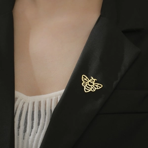 Gros plan d'une épingle à revers abeille dorée au design ajouré sur un blazer noir chic