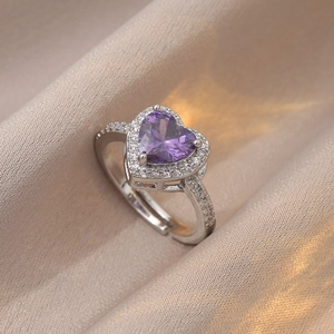Détail macro d'une bague coeur violet en zircon avec anneau réglable en argent sur soie