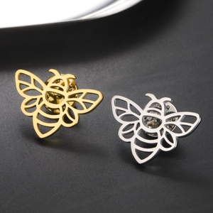 Macro détaillée de broches abeilles en or et argent avec lignes métalliques ajourées