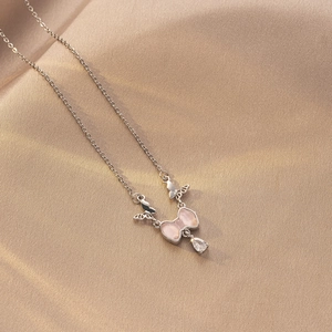 Detalle de collar de titanio plateado con colgante de mariposa rosa y circón de pera