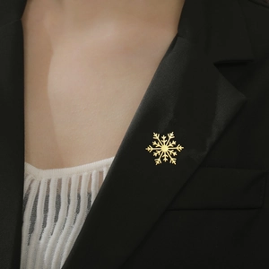 Détail d'une broche flocon de neige dorée épinglée sur le revers d'un costume noir