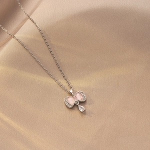 Detalle de cerca del colgante de mariposa con gema rosa y cristal en forma de gota