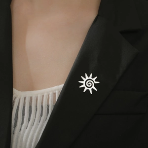 Détail d'une broche soleil argentée avec texture en spirale sur le revers d'un complet