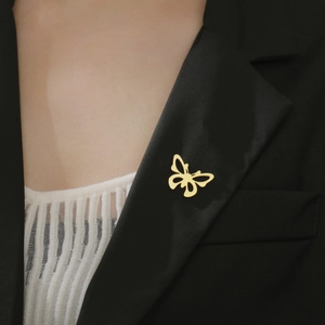 Gros plan d'une broche papillon dorée minimaliste sur le revers d'un costume noir