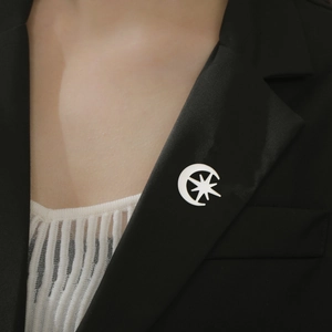 Détail d'une broche lune et étoile argentée épinglée sur le revers d'un costume noir