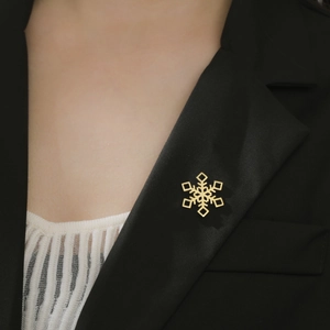 Détail d'une broche flocon de neige dorée sur le revers d'un costume noir pour un style chic