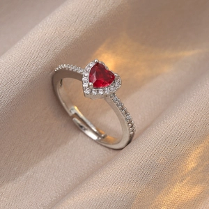 Macro d'une bague coeur réglable avec pierre de zircon rouge sur soie couleur champagne