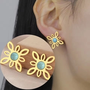 Macro detail of golden bohemian flower stud earrings with turquoise stone inlay on model