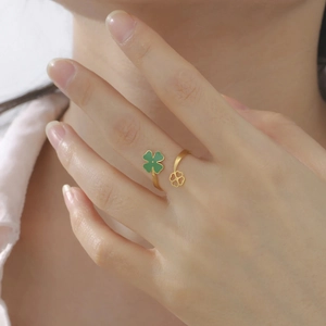 Detailed view of an adjustable gold open ring with green enamel four-leaf clover motifs