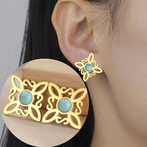 Detail of vintage gold Celtic knot earrings with turquoise gemstone inlay on model