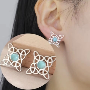Macro detail of silver Celtic witch knot stud earring with a light blue gemstone inlay