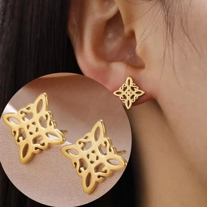 Macro shot of gold Celtic knot earrings showcasing hollow geometric design and metal texture