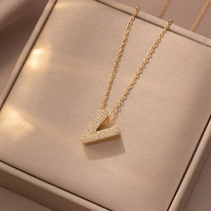 Macro detail of gold-plated V-shaped letter pendant with zircon stones on necklace