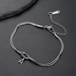 Detail van zilveren roestvrijstalen dubbele slangenketting armband met knoop en letter A