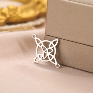 Macro shot of silver-colored Celtic knot pendant on champagne silk fabric background