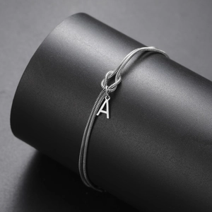 Detail van de zilveren slangenketting armband met knoopontwerp en letter A hanger