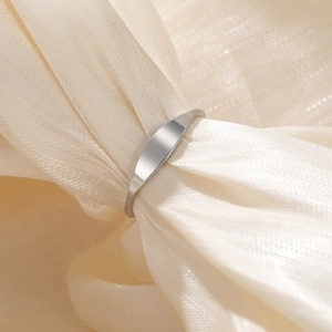 Polished silver stainless steel ring displayed on soft golden silk fabric texture