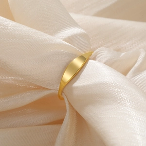 Close-up of polished gold-plated ring with curved rectangular panel on champagne silk