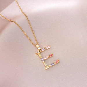 Vue détaillée du pendentif lettre E doré orné de zircons multicolores sur satin élégant