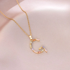 Gros plan du collier lettre G dorée orné de zircons colorés de taille baguette