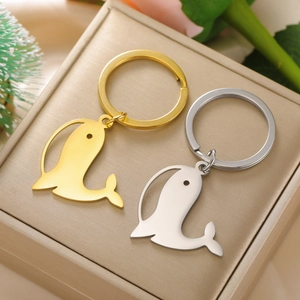 Paire de porte-clés baleine en acier poli or et argent sur un coffret cadeau chic