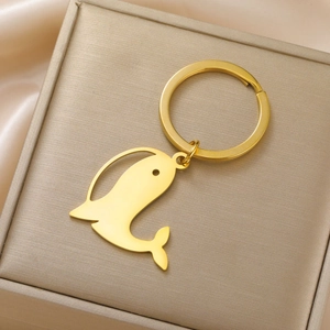 Détail d'un porte-clés en forme de baleine dorée dans un coffret cadeau élégant champagne