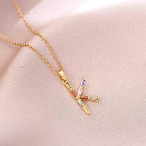 Macro d'un collier doré avec pendentif lettre K orné de pierres précieuses colorées