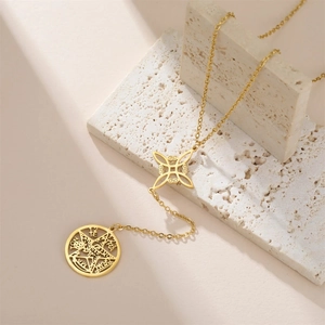 Macro shot of gold witch knot and pentagram double pendant on stone background