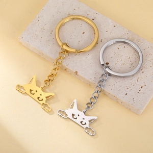 Cute gold and silver hollow kitten pendants on keychains displayed on a stone plate