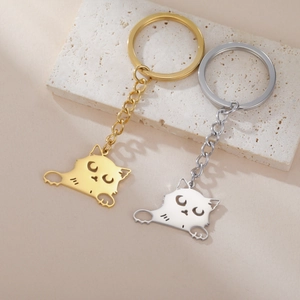 Cartoon kitten 304 stainless steel keychain in gold and silver set on stone surface