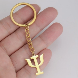 Detailed view of hand-held gold Psi symbol pendant on stainless steel keychain