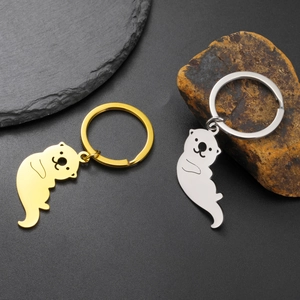 Porte-clés loutre en acier inoxydable poli, coloris or et argent sur fond de pierre