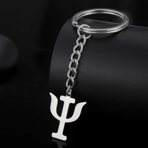 Close-up of polished stainless steel Psi symbol keychain on a black pedestal