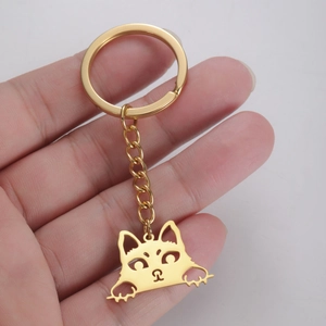 Detail view of gold stainless steel kitten charm keychain held in hand for scale