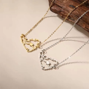 Detailed view of hollow UAE map pendant necklace in gold and silver finish on wooden block