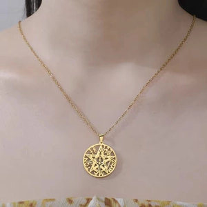 Detailed view of golden stainless steel pentagram pendant with occult lettering